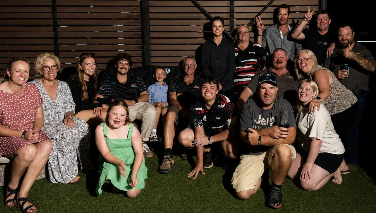 A large group of family, friends and archers together in the evening, several wearing Big Fella's Bow Strings shirts.