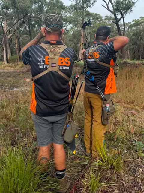 Two archers in Big Fella's shirts heading out into the scrub.