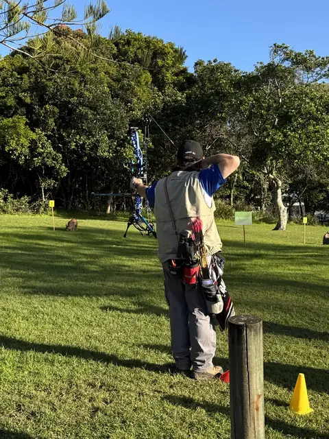 An archer lining up a long shot across a mown range with targets in the distance.