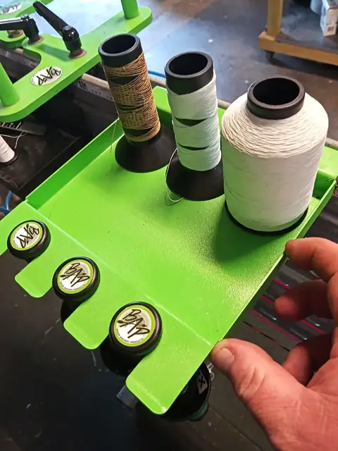 Serving thread spools in a green holder on the bench.