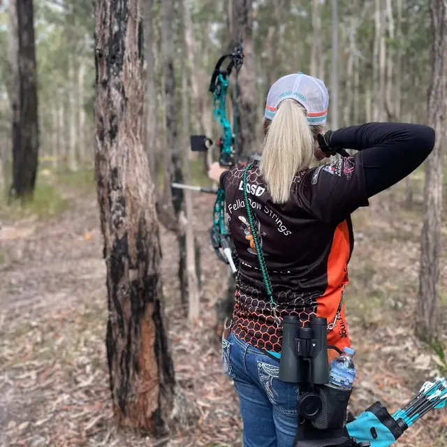An archer at full draw down a shooting lane cut through the trees.