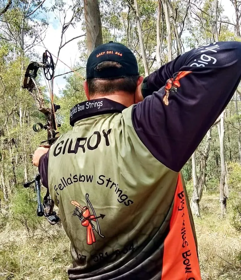 An archer at full draw wearing a Big Fella's Bow Strings jersey with GILROY across the back.