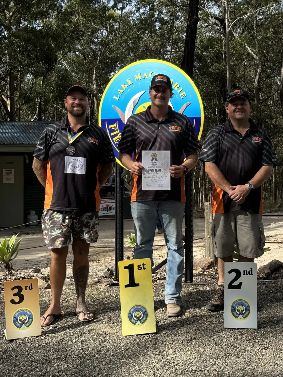 Three archers in Big Fella's shirts on a podium, first, second and third, holding trophies.
