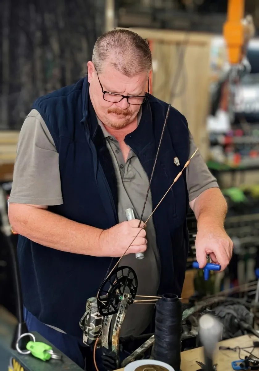 Tim measuring a bow in the workshop.